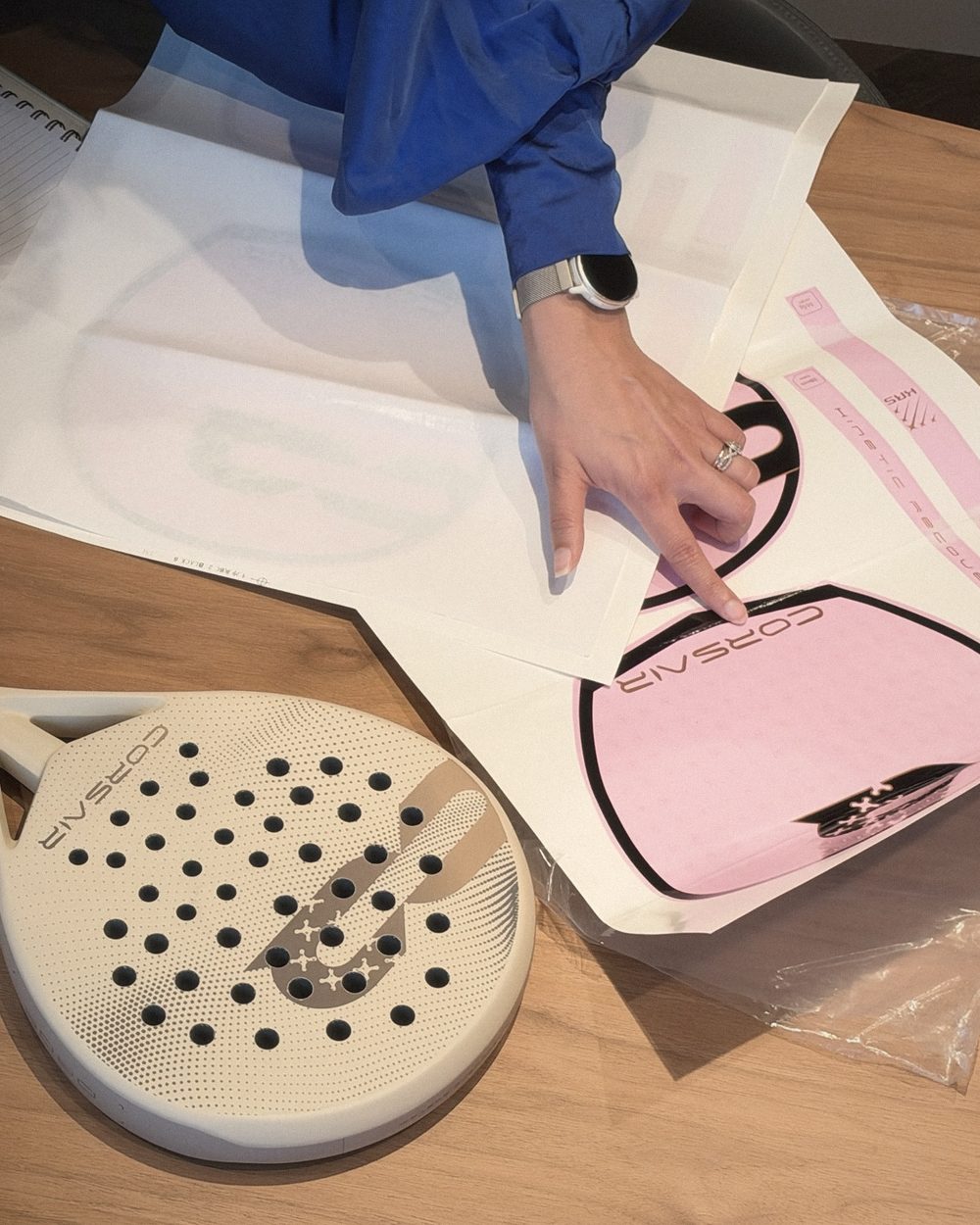A hand on the pink APEX decal proof, beside DROP and the tracing-paper studies